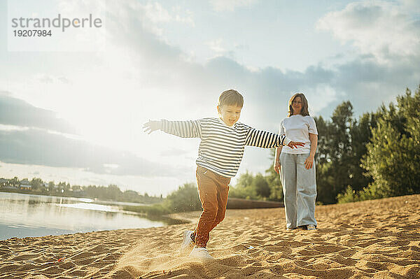 Sohn spielt am Strand  Mutter steht im Hintergrund