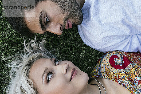 Romantic couple staring at each other lying on grass