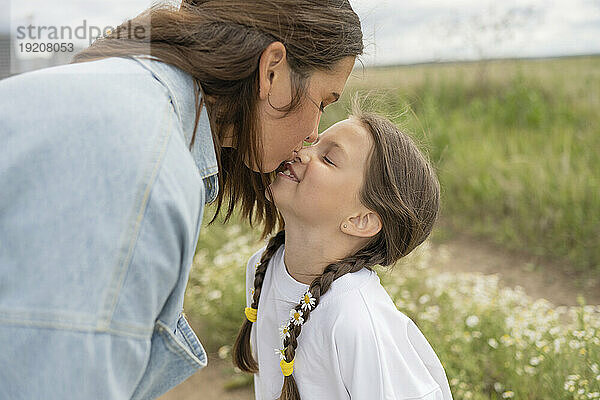Mutter küsst glückliche Tochter in der Natur