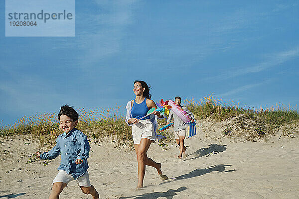 Glückliche Familie  die zusammen am Strand läuft