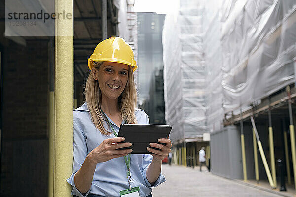 Lächelnder Ingenieur hält Tablet-PC auf der Baustelle