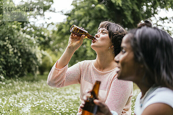 Happy friends drinking beer in park
