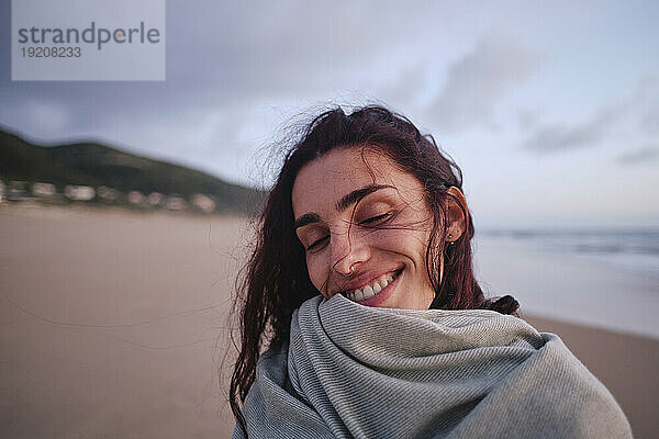 Glückliche Frau mit geschlossenen Augen am Strand