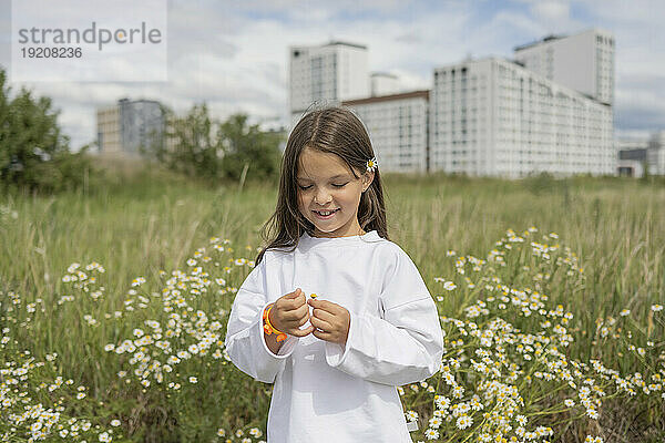 Glückliches Mädchen mit Gänseblümchen auf der Wiese an einem sonnigen Tag