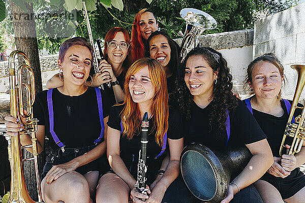 Fröhliche Frauen-Volksmusikgruppe sitzt zusammen und hält Blasinstrumente