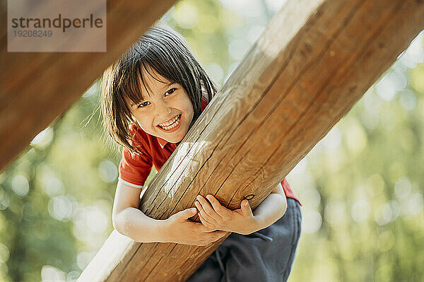 Smiling boy playing on wooden log