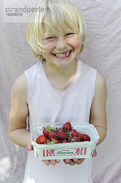 Lächelndes Mädchen hält frische Erdbeeren aus dem Garten