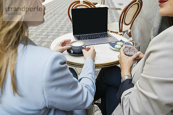 Geschäftsfrauen sitzen und diskutieren im Straßencafé