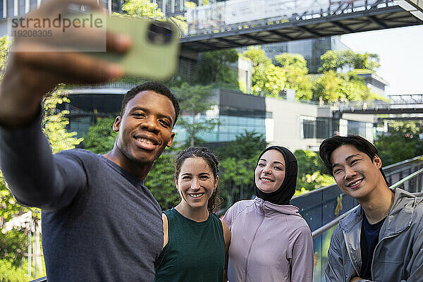 Lächelnder Mann  der mit Freunden ein Selfie per Smartphone macht