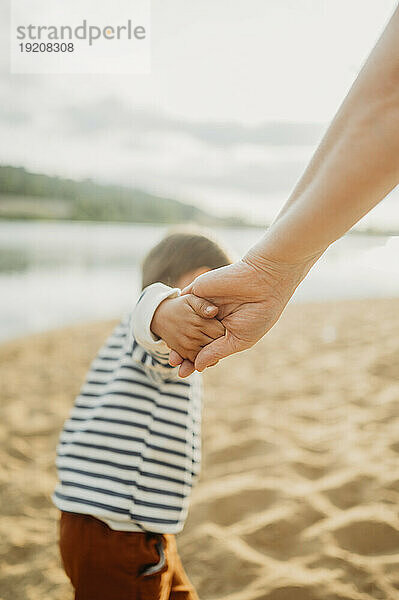 Mother and son holding hands and walking at beach