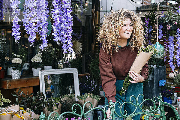 Lächelnde Geschäftsfrau hält Blumenstrauß im Blumenladen