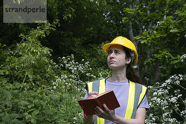 Nachdenklicher Arbeiter schreibt Tagebuch vor Bäumen