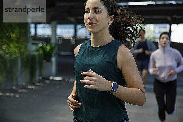 Frau mit Smartwatch joggt mit Freunden