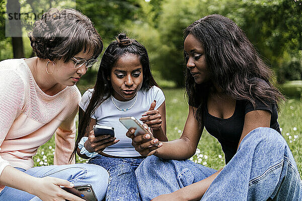 Frau diskutiert mit Freunden über Smartphone im Park