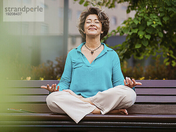 Mature businesswoman meditating on park bench