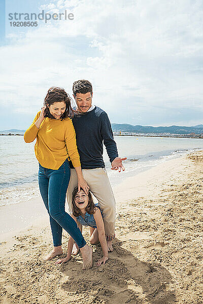 Glückliches Mädchen  das mit Vater und Mutter am Strand genießt