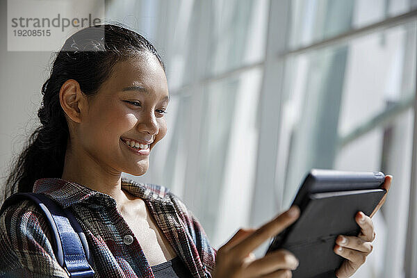 Smiling student using tablet PC in university