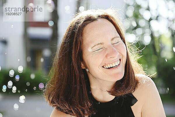 Happy woman laughing with eyes closed at sunny day