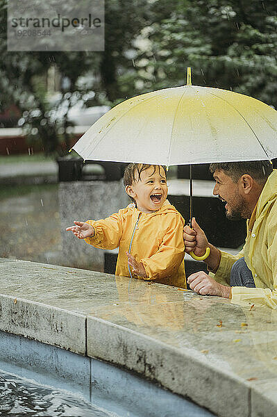 Vater und Sohn amüsieren sich im Regen im Park