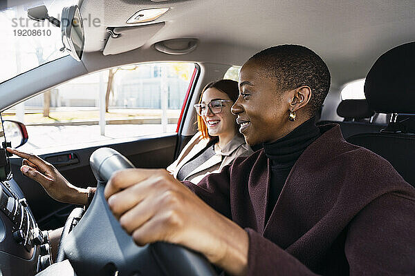 Happy woman using smart phone with colleague in car