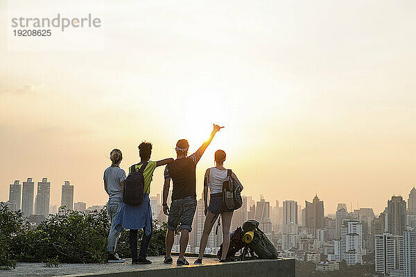 Freunde genießen den Blick auf den Sonnenuntergang vom Dach