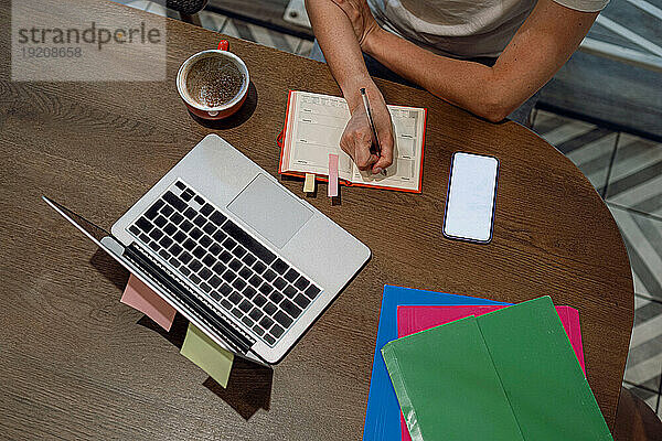 Geschäftsfrau schreibt am Laptop am Tisch im Café Tagebuch