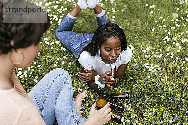 Woman drinking beer with friend at park