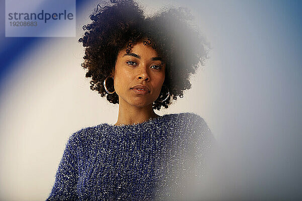 Young woman with Afro hairstyle against colored background