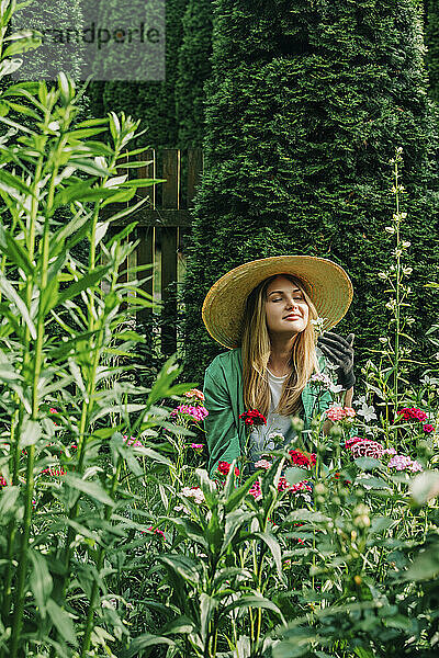 Lächelnde Frau riecht Blumen im Garten