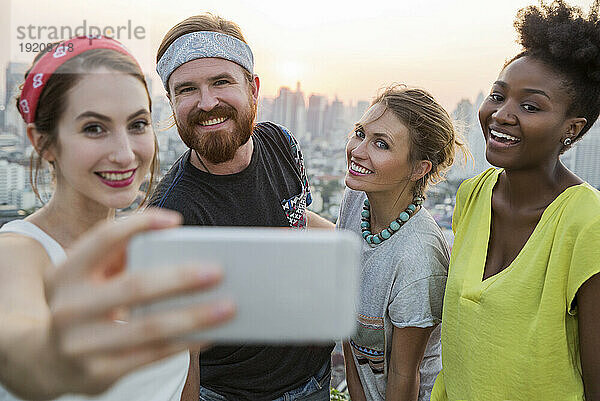Frau macht Selfie mit Freunden bei Sonnenuntergang
