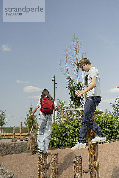 Freunde balancieren auf Holzpfahl auf Spielplatz