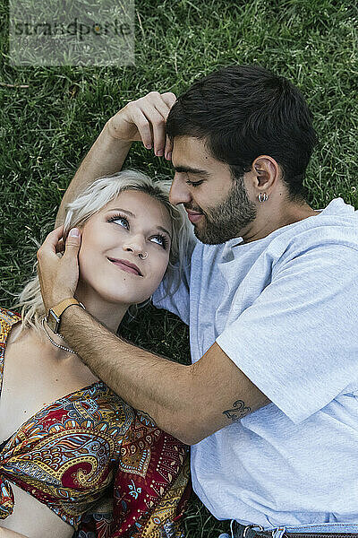 Loving young couple lying on grass in park