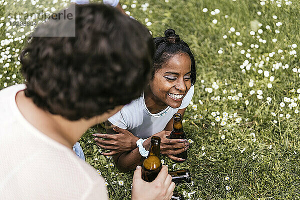 Junge Frau genießt Bier mit Freund im Park