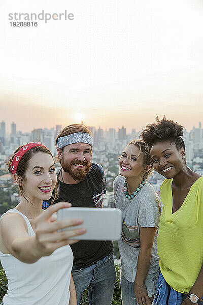 Frau macht Selfie mit Freunden vor dem Sonnenuntergangshimmel