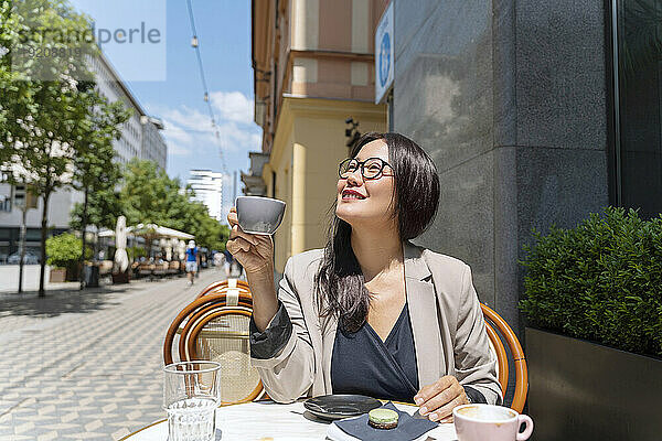 Lächelnde Geschäftsfrau genießt Kaffee im Straßencafé