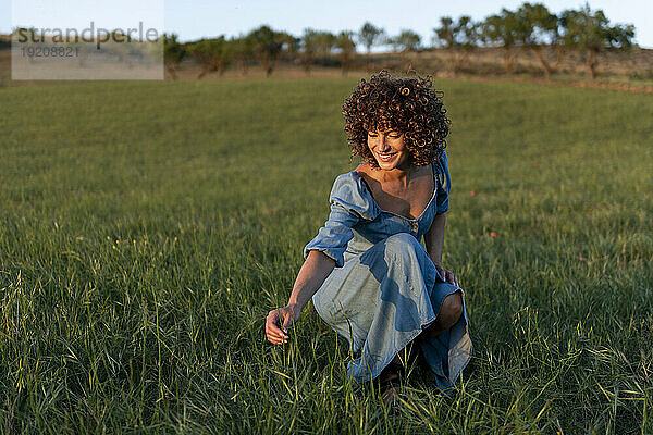 Lächelnde Frau pflückt Gras auf der Wiese
