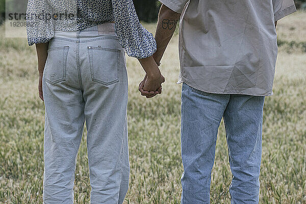 Young couple holding hands standing in park