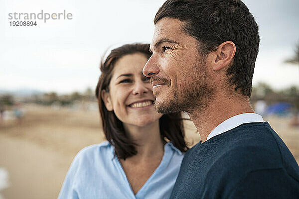 Glücklicher Mann und Frau am Strand vor dem Himmel