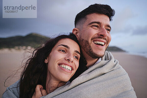 Glückliches Paar lacht gemeinsam am Strand