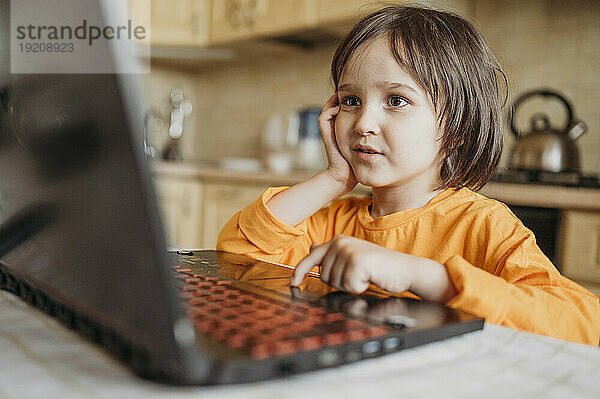 Neugieriger Junge benutzt Laptop zu Hause