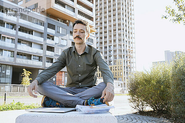 Geschäftsmann meditiert im Schneidersitz im Büropark