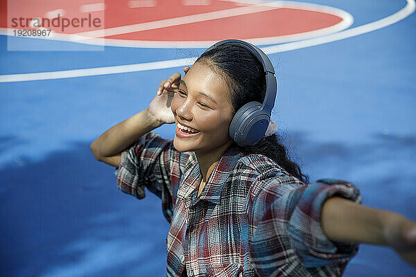 Lächelnder Student  der auf dem Spielplatz Musik hört