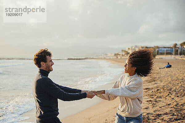 Glückliches Paar hält Händchen und hat Spaß am Strand