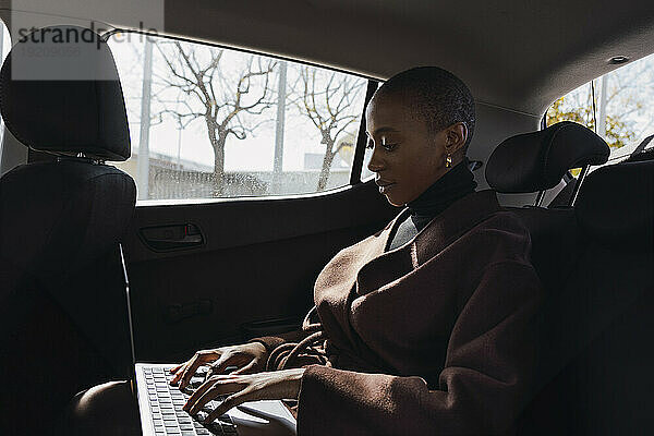 Geschäftsfrau arbeitet im Auto am Laptop