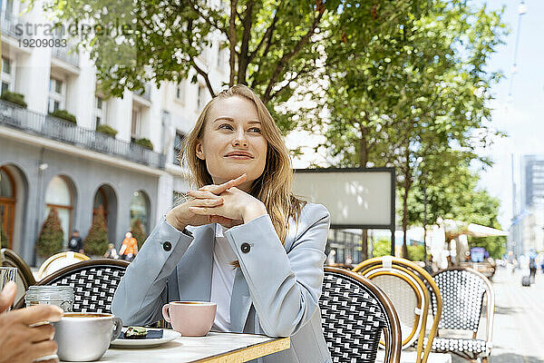 Nachdenkliche Geschäftsfrau sitzt im Straßencafé