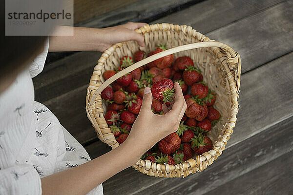 Mädchen untersucht Erdbeere aus Korb