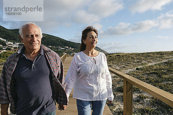Glückliches älteres Paar  das Händchen haltend auf der Promenade unter freiem Himmel spaziert