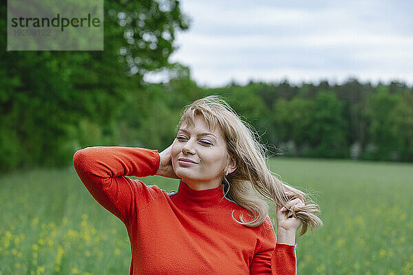 Lächelnde Frau steht im Grasbereich