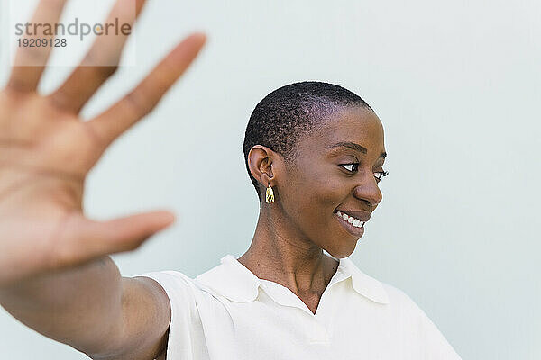 Glückliche junge Frau zeigt Stopp-Geste vor weißem Hintergrund