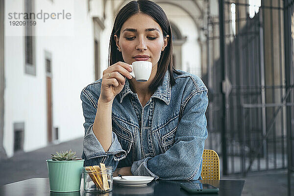 Frau sitzt und trinkt Kaffee im Café